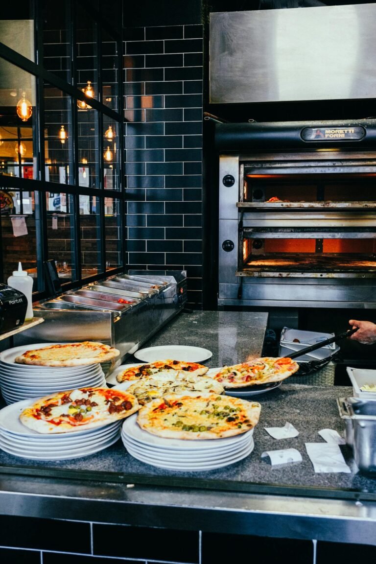 Mouthwatering pizzas on plates in a vibrant restaurant kitchen setting with an open oven.
